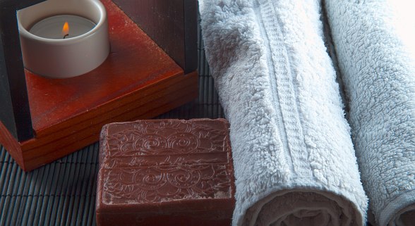 Relax with a scented candle, soothing soap, and soft rolled towels—perfect for a calming spa experience.