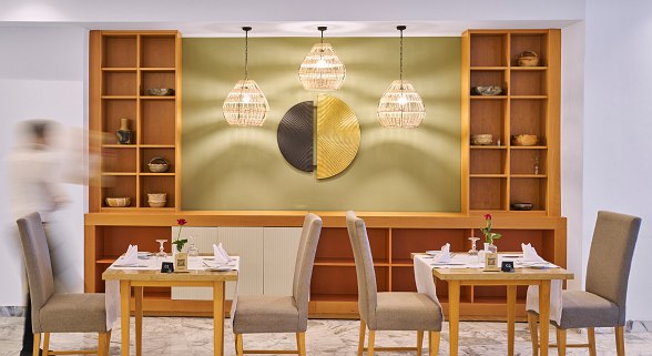 Modern, bright hotel restaurant with white marble tiles, decorative walls and plenty of seating.