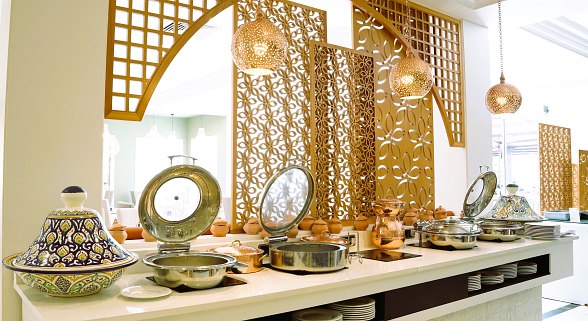 Modern, bright hotel restaurant with white marble tiles, decorative walls and plenty of seating.