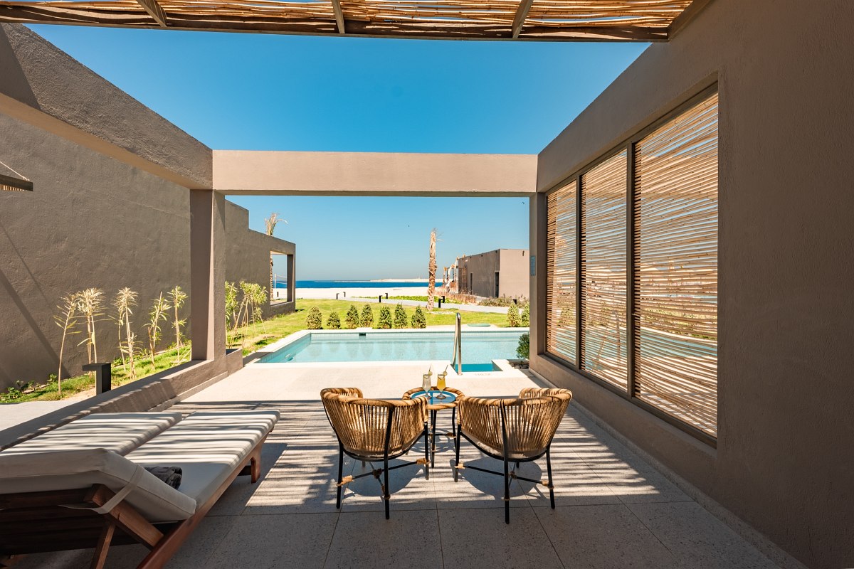 ‘Furnished balcony with sea view, two chairs and table, view of whirlpool and sandy beach