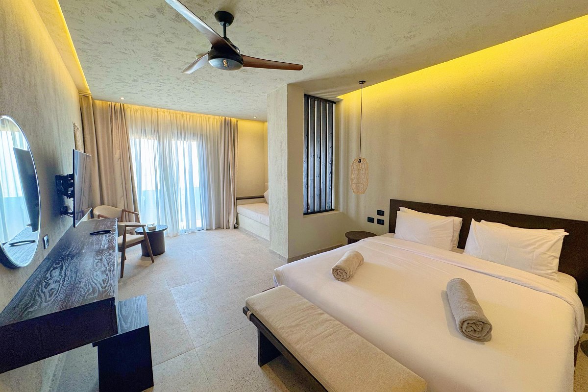 ‘Spacious hotel room with double bed, sofa, ceiling fan and stylish lighting.’