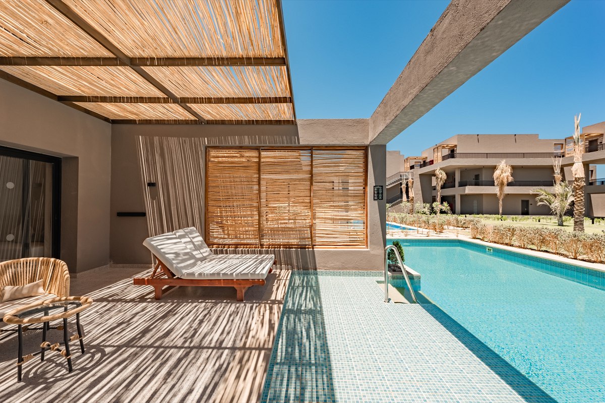 Modern suite with terrace, pool access, loungers and seating area, view of the dunes and the sea.