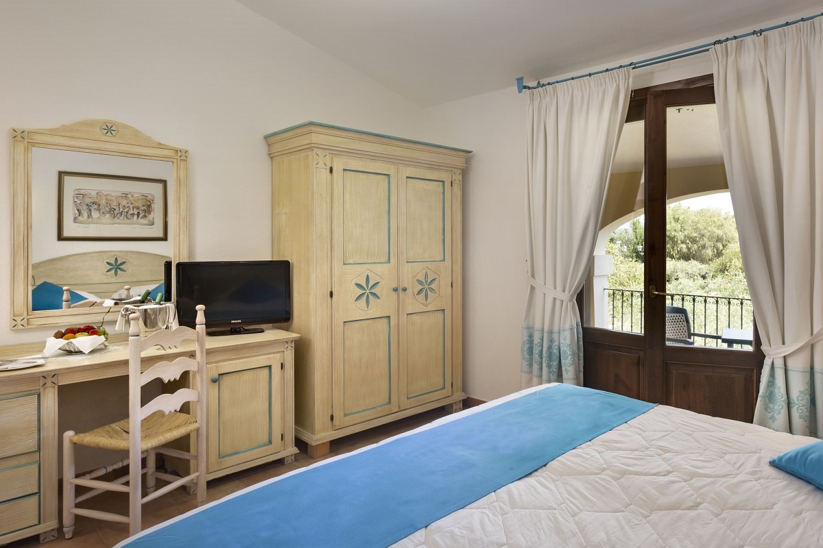 Charming hotel room with desk, TV, closet and balcony with a view of the countryside.