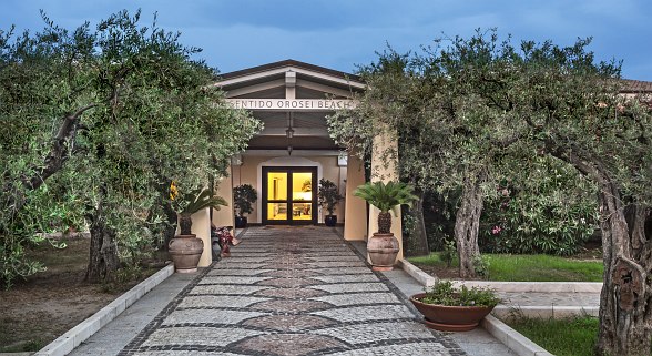 Hotel Sentido Orosei Beach, Hotel entrance with paved path, Mediterranean plants and atmospheric lighting - inviting and well-kept.