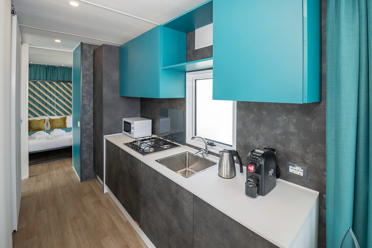 Modern kitchen unit with cooker, sink, coffee machine, microwave and blue wall unit - functional and stylish.