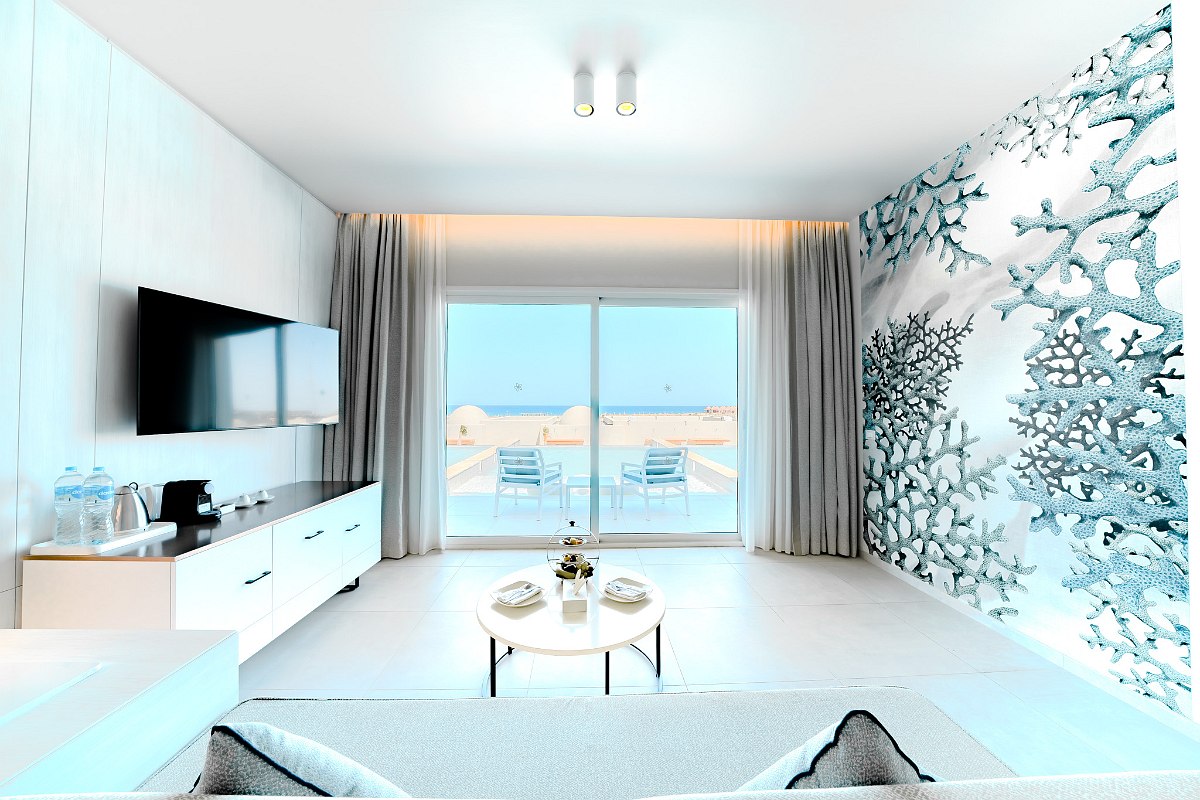 Modern bathroom with a white vanity, round mirror, marble wall, and a tall gold-framed mirror opposite the sink. Clean and minimalistic design.